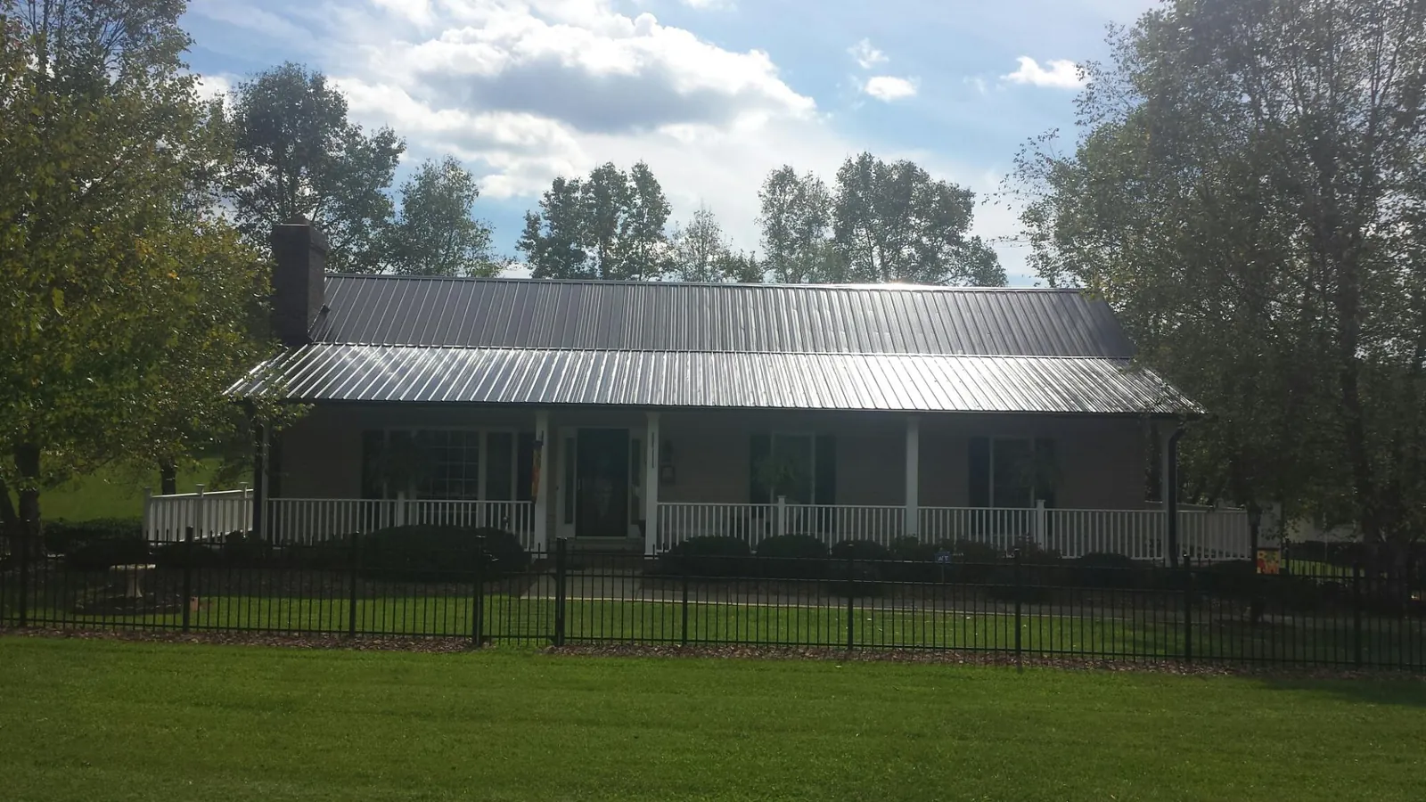 Gray metal roof on a brick ranch with a full width front porch — Gutter Guard Installation work by our crew in Callahan