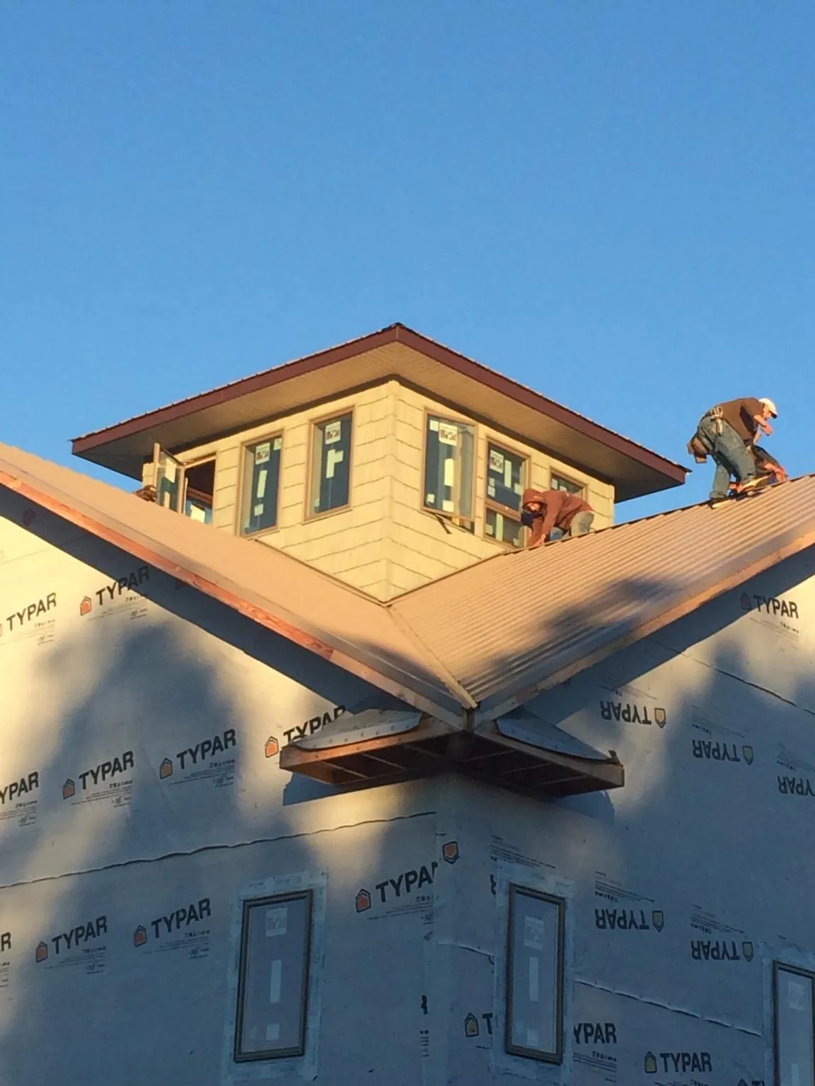 Roofers working around a rooftop cupola on a new metal roof at sunset — Roof Waterproofing in Callahan by Roofing Brothers